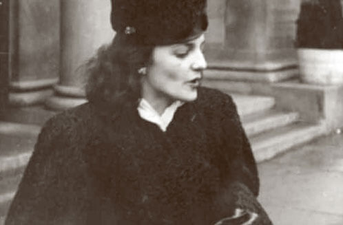 Vintage black and white photo of a woman with dark, curly hair in a black fur coat and hat